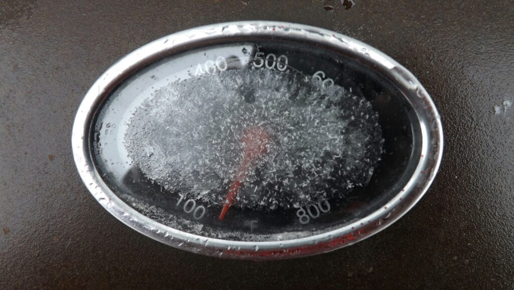 Digital BBQ thermometer measuring grate-level temperature inside a smoker