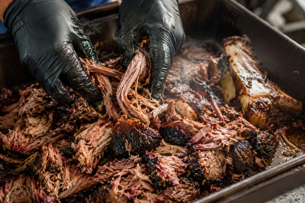 Pulling rested smoked pork butt into tender strands and bark pieces